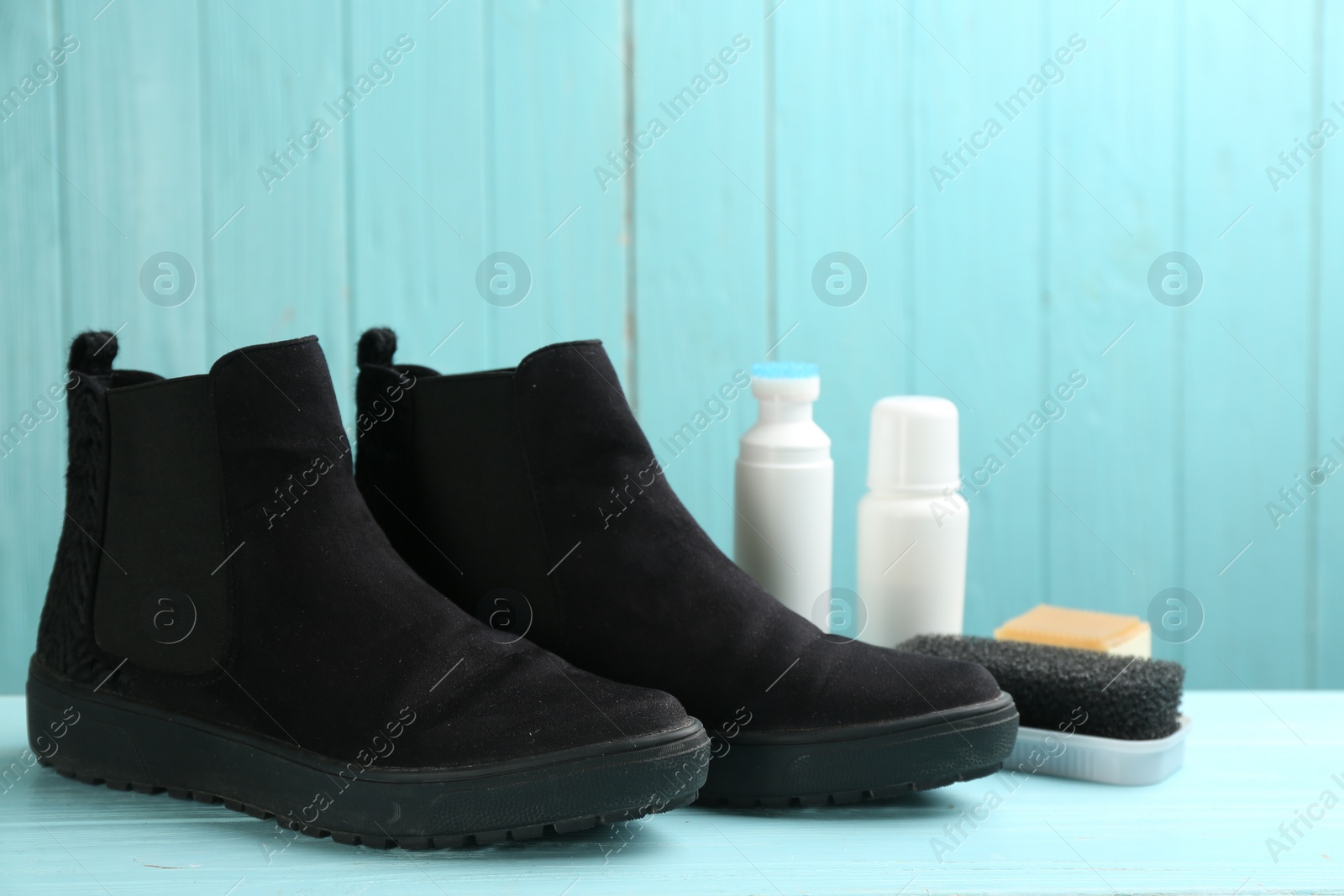 Photo of Stylish footwear with shoe care accessories on light blue wooden table