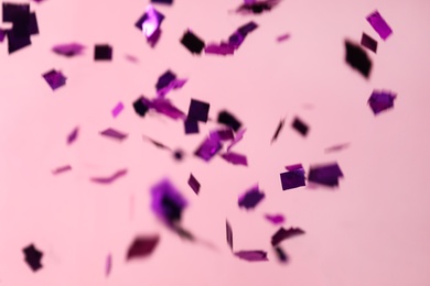 Photo of Shiny purple confetti falling down on pink background