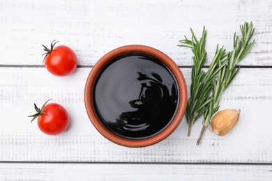 Photo of Organic balsamic vinegar and cooking ingredients on white wooden table, flat lay