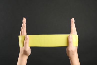 Woman with fitness elastic band on black background, closeup