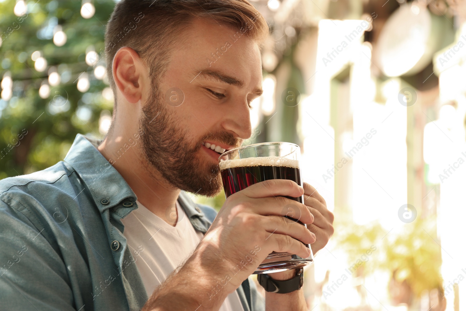 Photo of Handsome man with cold kvass outdoors. Traditional Russian summer drink