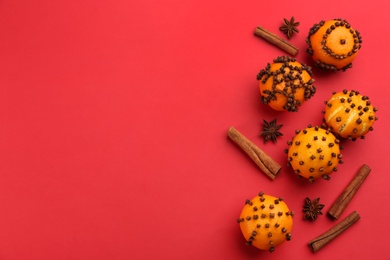 Flat lay composition with pomander balls made of fresh tangerines on red background. Space for text
