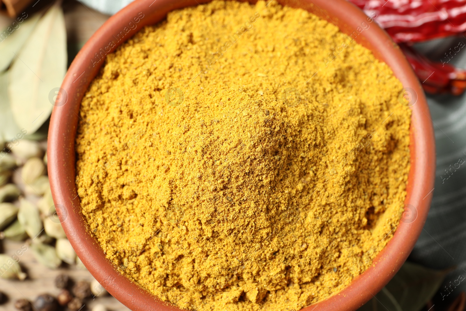 Photo of Curry powder in bowl and other spices on table, top view