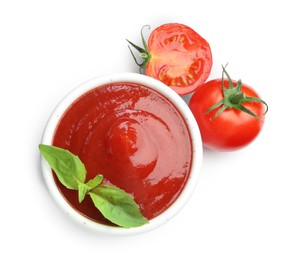 Photo of Tasty ketchup in bowl, basil and fresh tomatoes isolated on white, top view