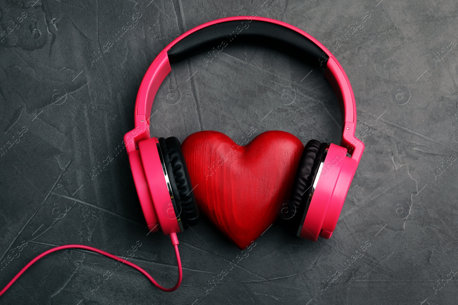 Photo of Decorative heart with modern headphones on dark background, top view