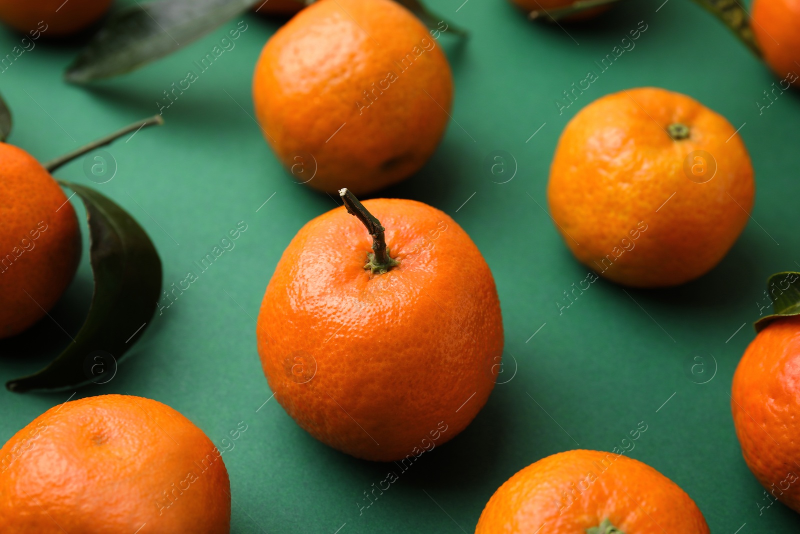 Photo of Fresh ripe tangerines on green background, closeup
