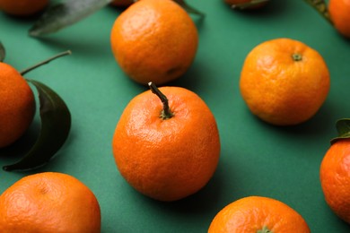 Photo of Fresh ripe tangerines on green background, closeup