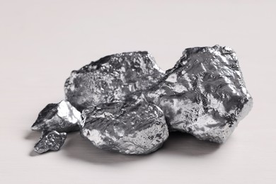 Photo of Pile of silver nuggets on white wooden table, closeup