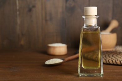 Fresh sesame oil in glass bottle and seeds on wooden table. Space for text