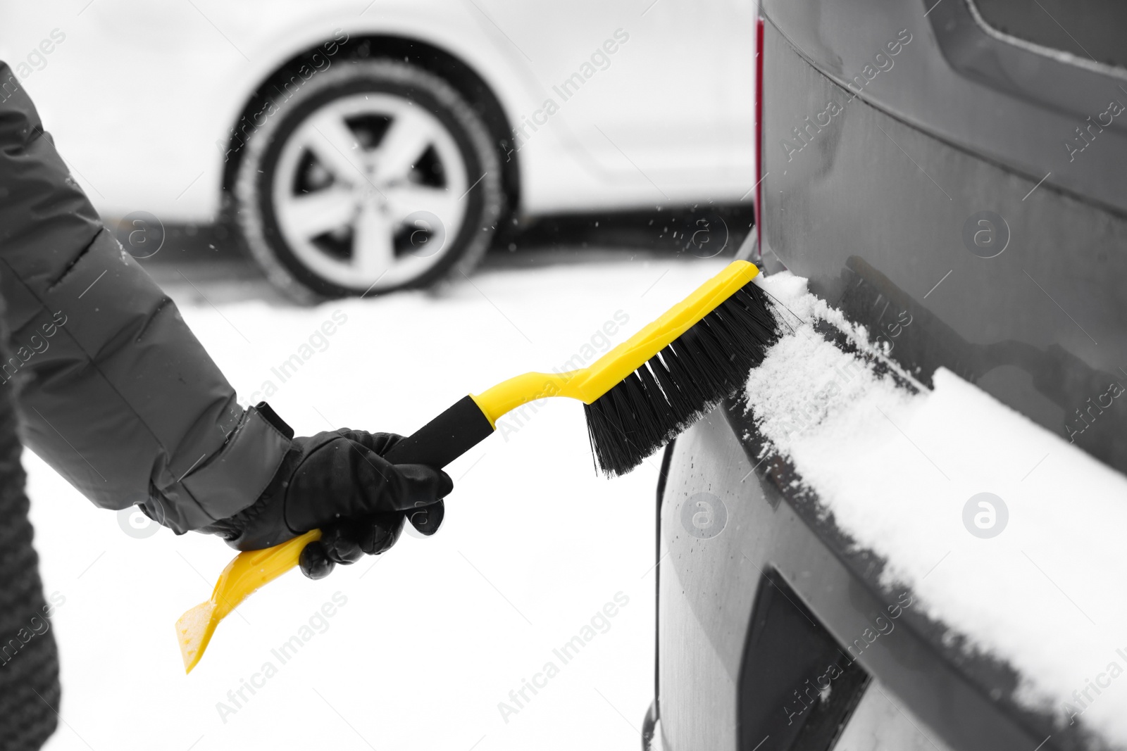 Photo of Man cleaning snow from car outdoors, closeup