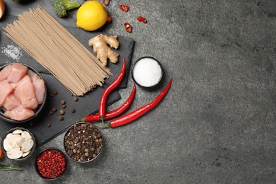 Different raw products and spices on grey table, flat lay. Space for text