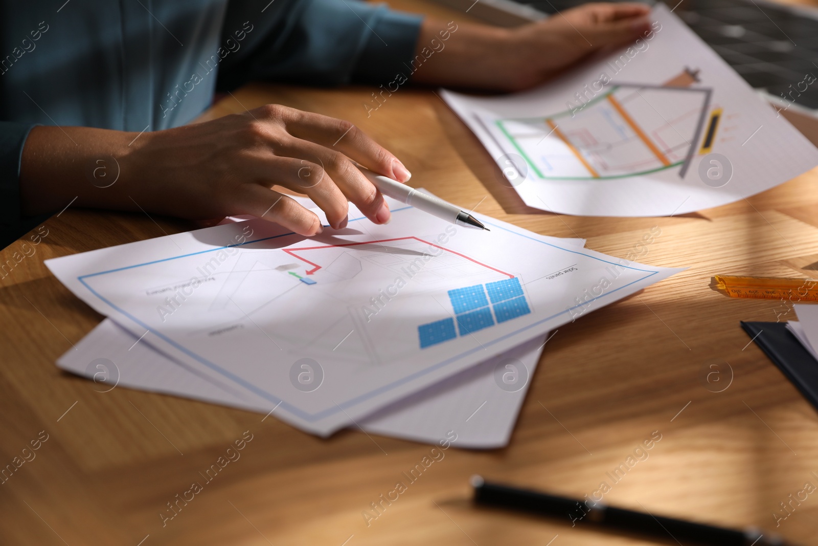 Photo of Woman working on house project with solar panels at table in office, closeup