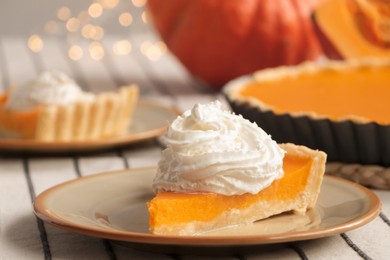 Photo of Piece of fresh homemade pumpkin pie with whipped cream on table