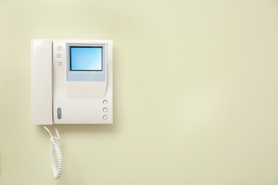 Photo of Modern intercom system with handset on light wall, space for text