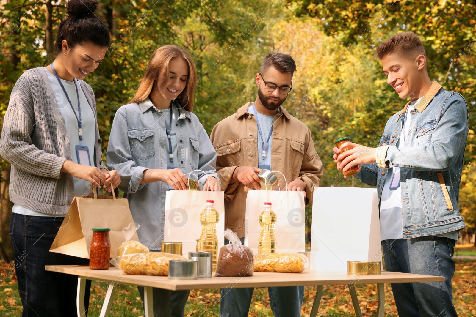 Photo of Group of volunteers packing food products at table in park