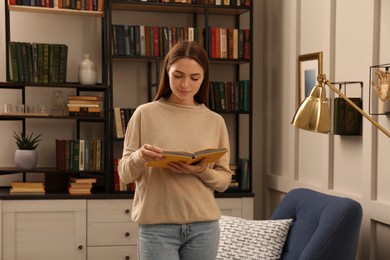 Young woman reading book in home library