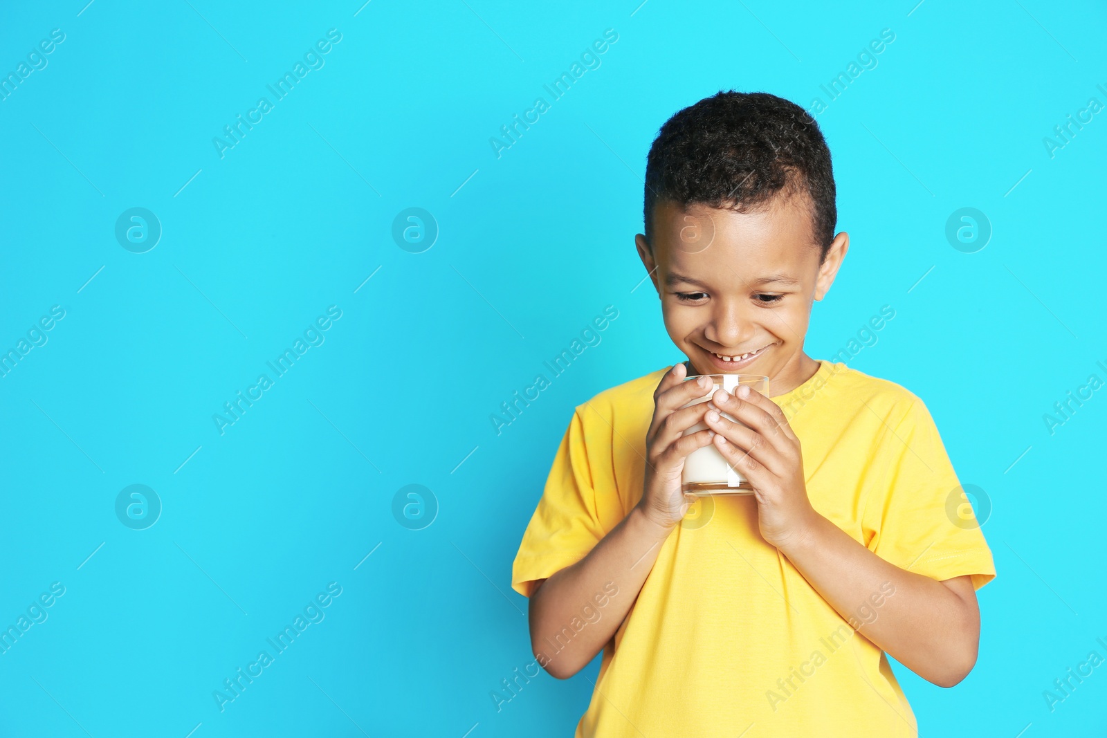 Photo of Adorable African-American boy with glass of milk on color background