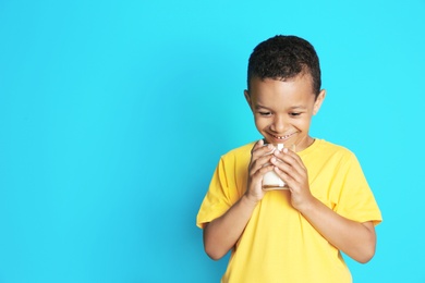 Photo of Adorable African-American boy with glass of milk on color background