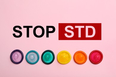 Image of Colorful condoms and text STOP STD on pink background, flat lay