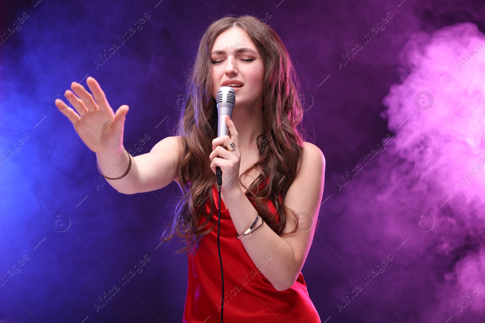 Photo of Emotional woman with microphone singing in color lights