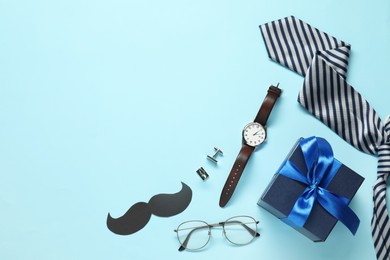 Photo of Paper mustache, gift box and men accessories on light blue background, flat lay with space for text. Father's day celebration