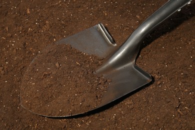 Photo of Metal shovel on fertile soil. Gardening tool