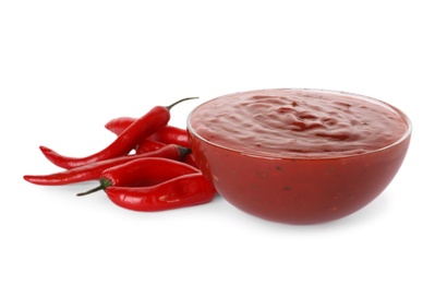 Photo of Glass bowl with red sauce and fresh chili peppers isolated on white