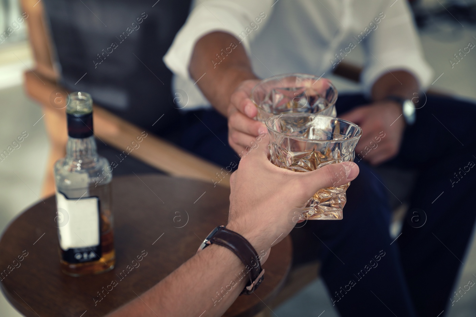 Photo of Young men drinking whiskey together at home, closeup