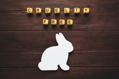 Photo of Cubes with text Cruelty Free and figure of rabbit on wooden table, flat lay. Stop animal tests