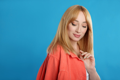 Photo of Beautiful young woman with blonde hair on blue background. Space for text