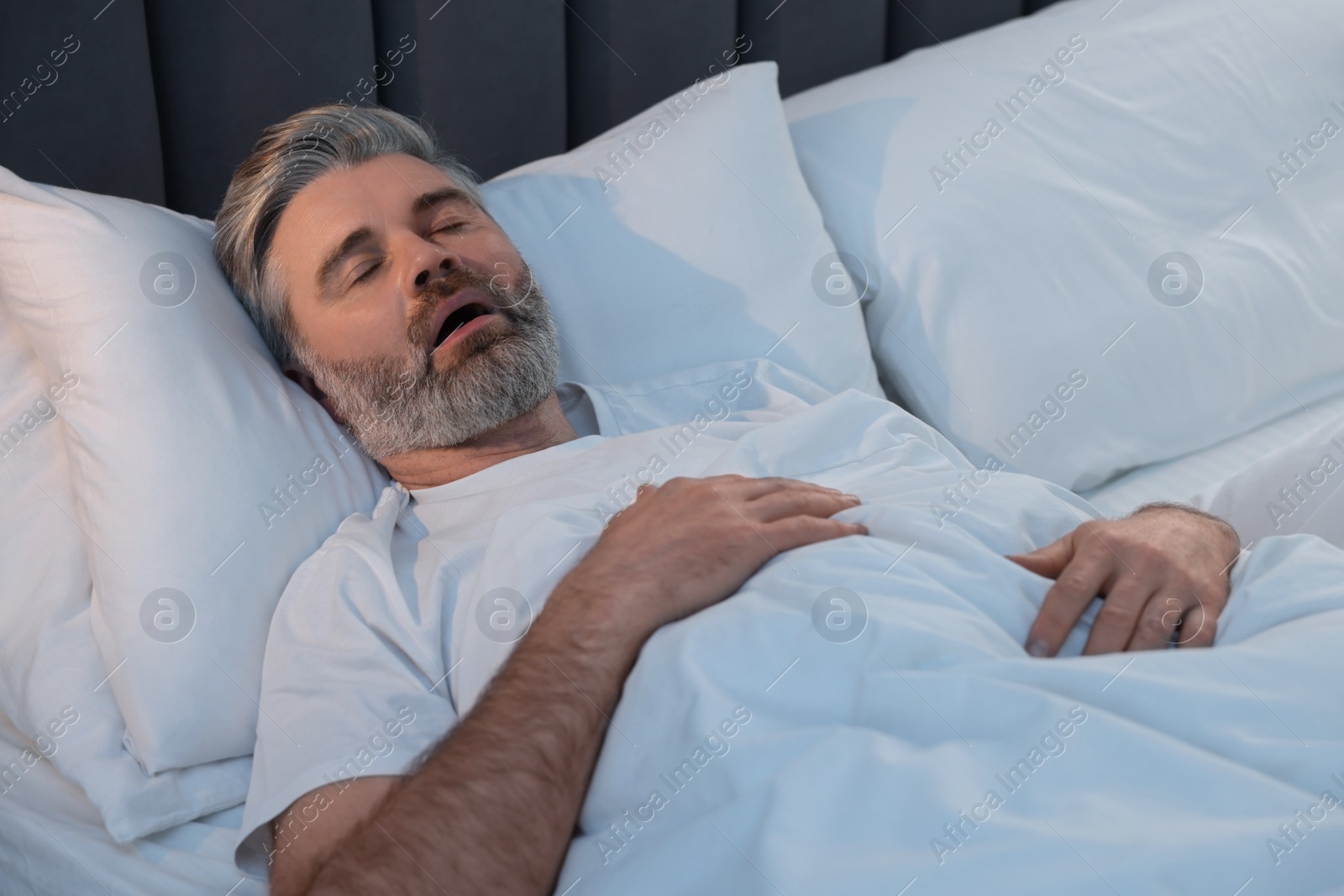 Photo of Man snoring while sleeping in bed at home