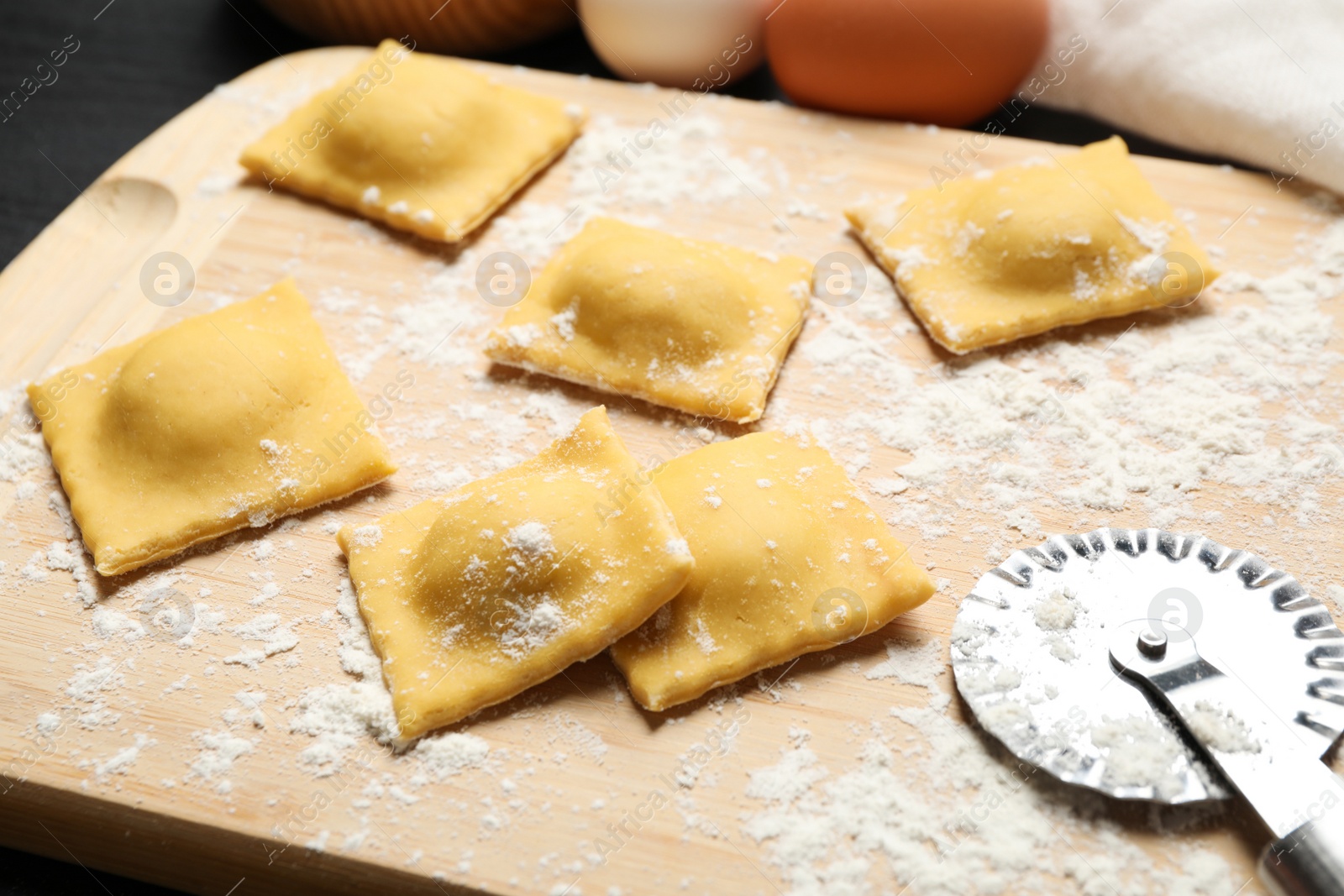 Photo of Raw ravioli on wooden board, closeup view. Italian pasta