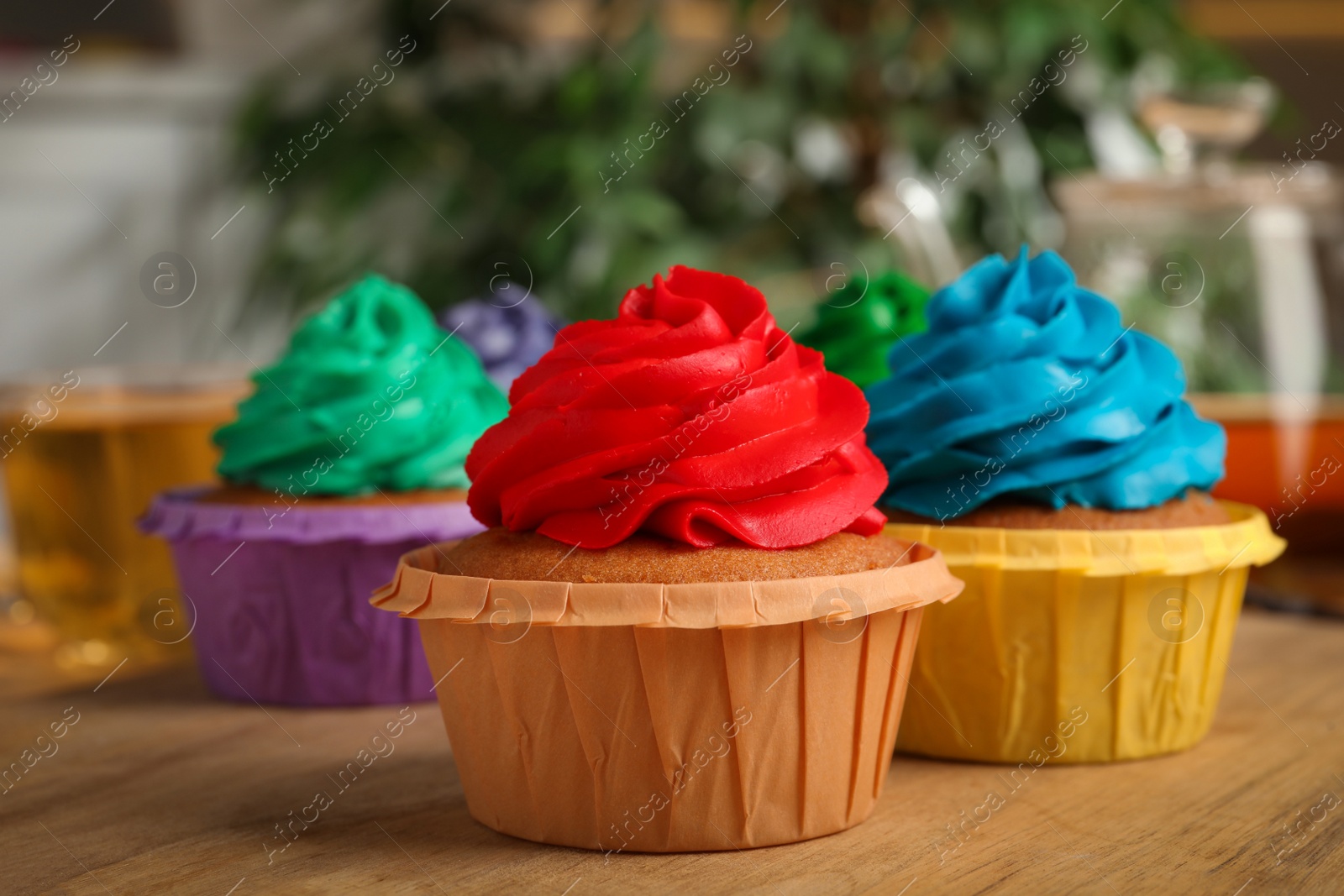 Photo of Delicious cupcakes with colorful cream on wooden table, closeup