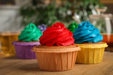 Delicious cupcakes with colorful cream on wooden table, closeup