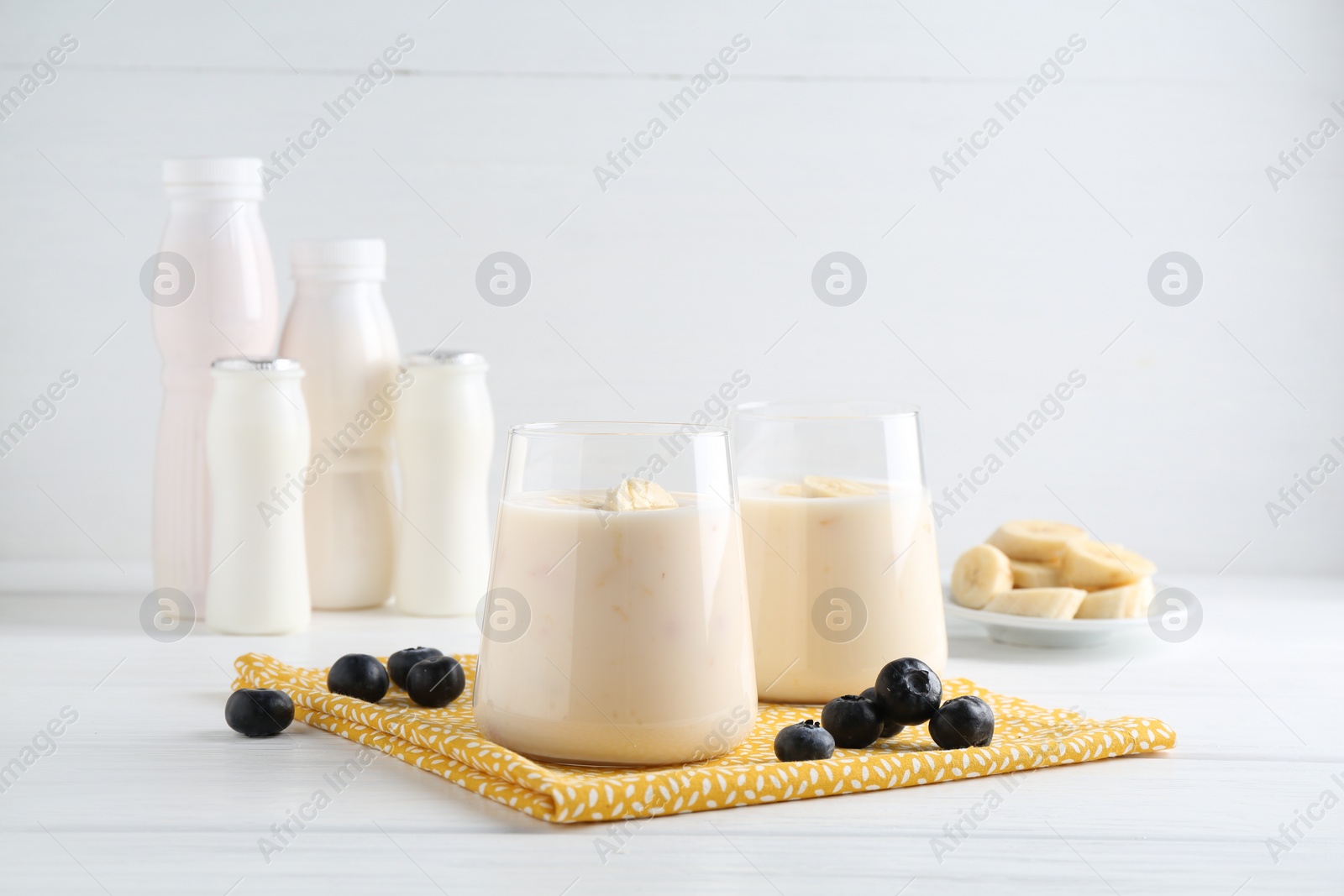 Photo of Tasty yogurt, banana and blueberries on white wooden table