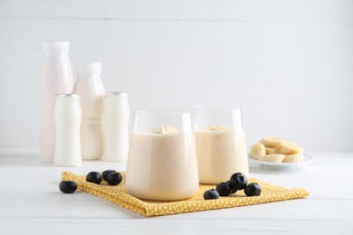 Tasty yogurt, banana and blueberries on white wooden table