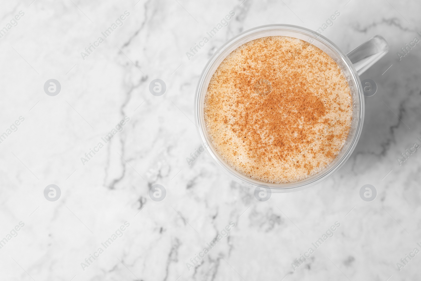 Photo of Glass cup of delicious eggnog on white marble table, top view. Space for text