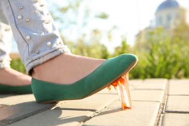 Photo of Woman stepping in chewing gum on sidewalk. Concept of stickiness