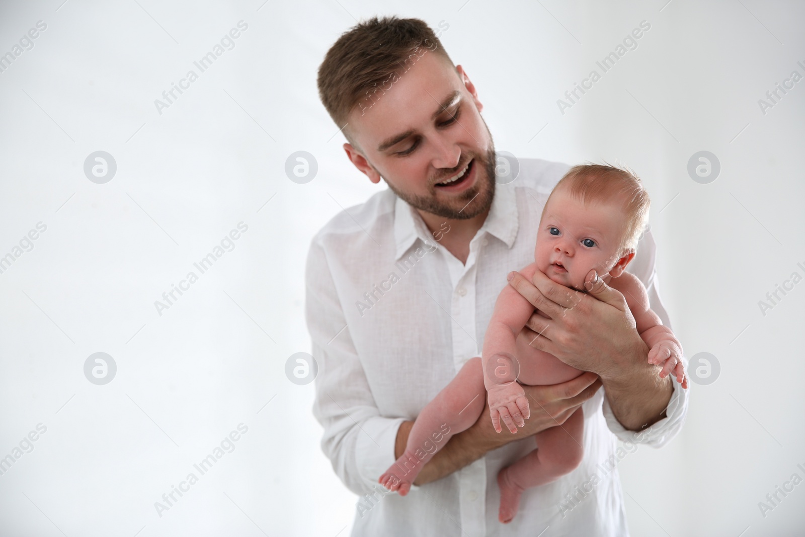 Photo of Father with his newborn son on light background