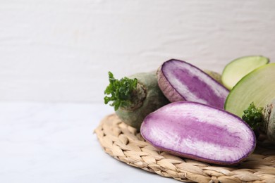 Photo of Green and purple daikon radishes on white table, closeup. Space for text