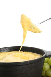 Photo of Dipping piece of apple into fondue pot with tasty melted cheese isolated on white