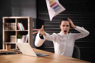 Photo of Emotional young businesswoman throwing papers at table in office. Hate and burnout concept