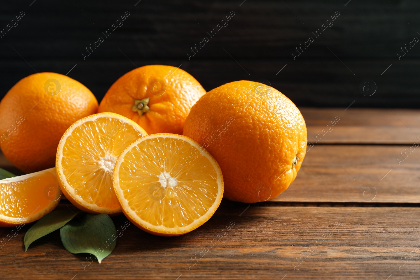 Photo of Fresh oranges with leaves on wooden table. Space for text