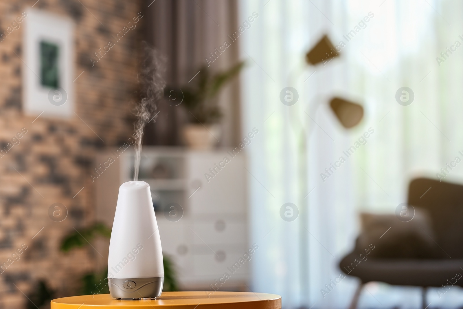 Photo of Aroma oil diffuser on table against blurred background. Air freshener