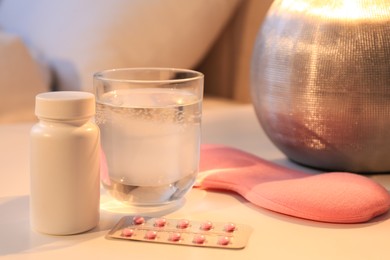 Photo of Sleeping mask, pills and glass of water on nightstand indoors. Insomnia treatment