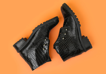 Pair of stylish ankle boots on orange background, top view