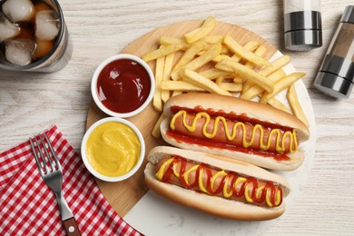 Photo of Delicious hot dogs with mustard, ketchup and potato fries on white wooden table, flat lay