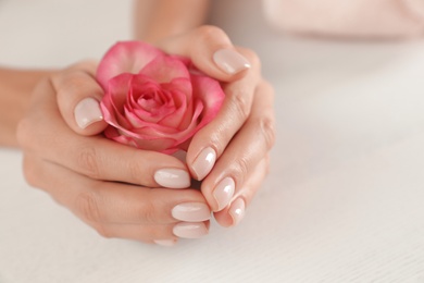 Photo of Woman holding flower at table, closeup with space for text. Spa treatment