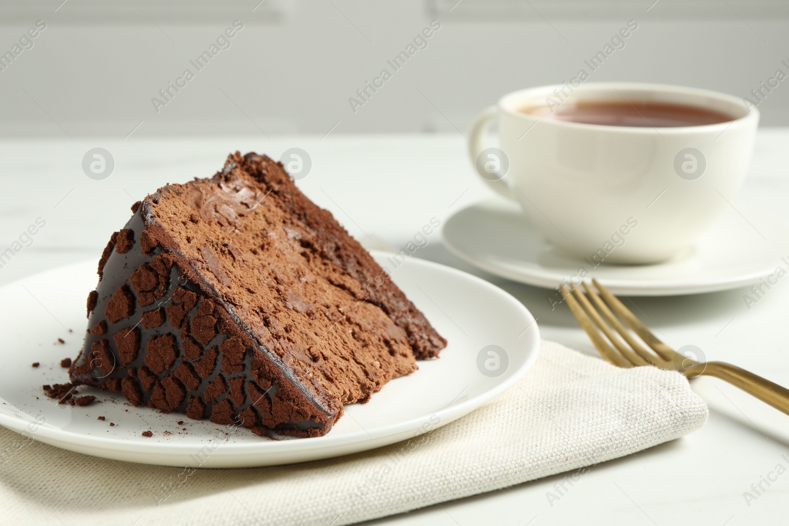 Photo of Piece of delicious chocolate truffle cake on white table, closeup