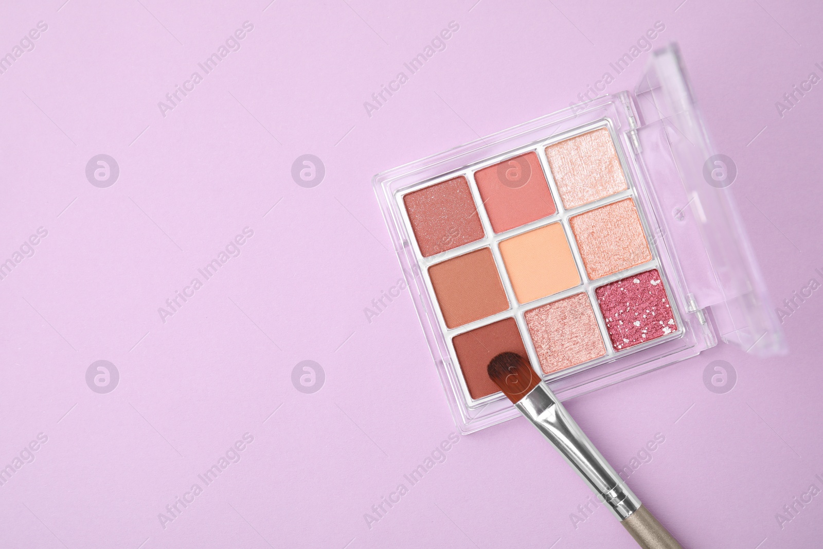 Photo of Beautiful eye shadow palette and brush on lilac background, top view. Space for text
